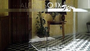 Entrada de hotel con suelo de cuadros, puerta de madera y señal que indica el camino a la recepción.