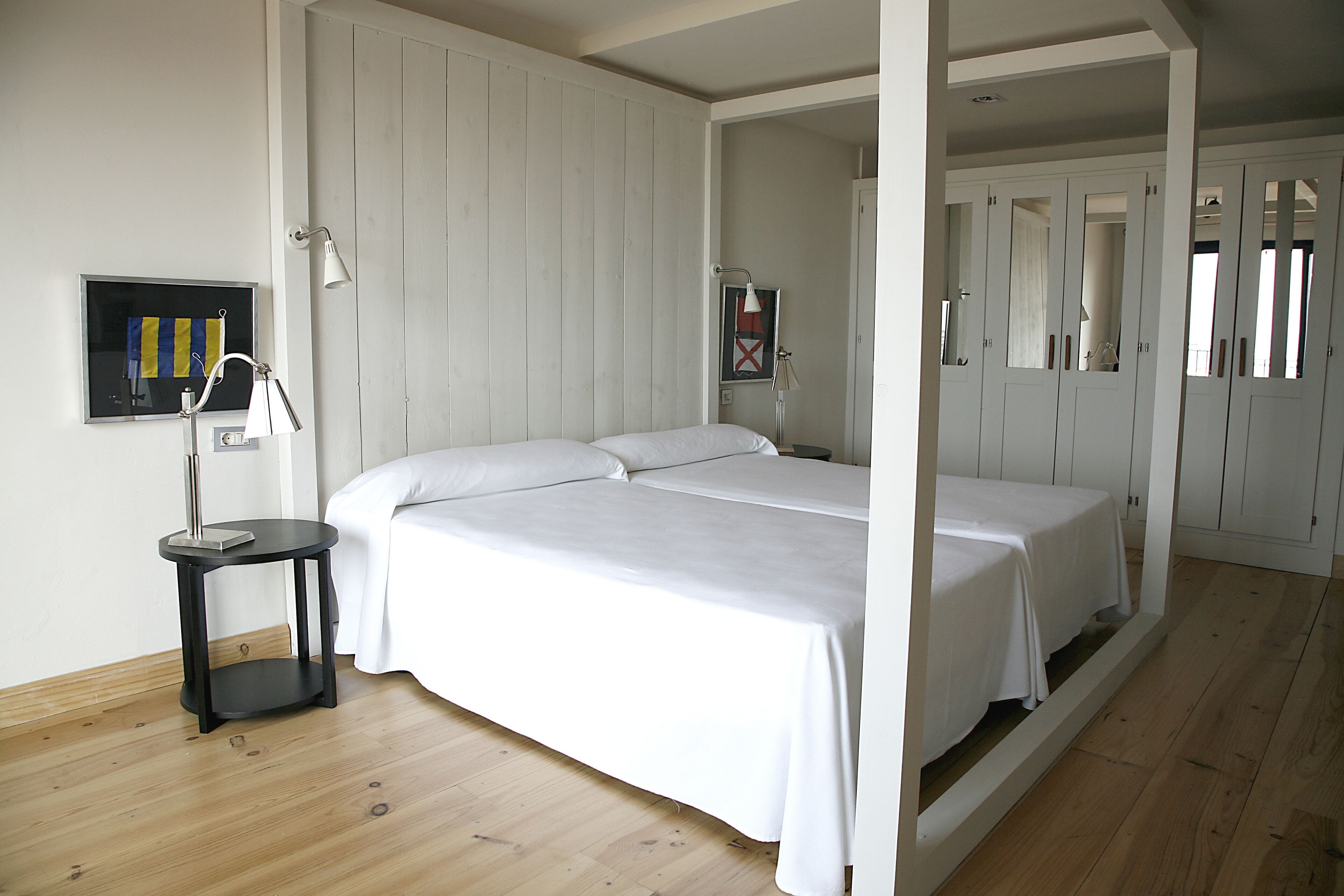 Un dormitorio con dos camas, una mesita de noche, una lámpara y un cuadro en la pared.