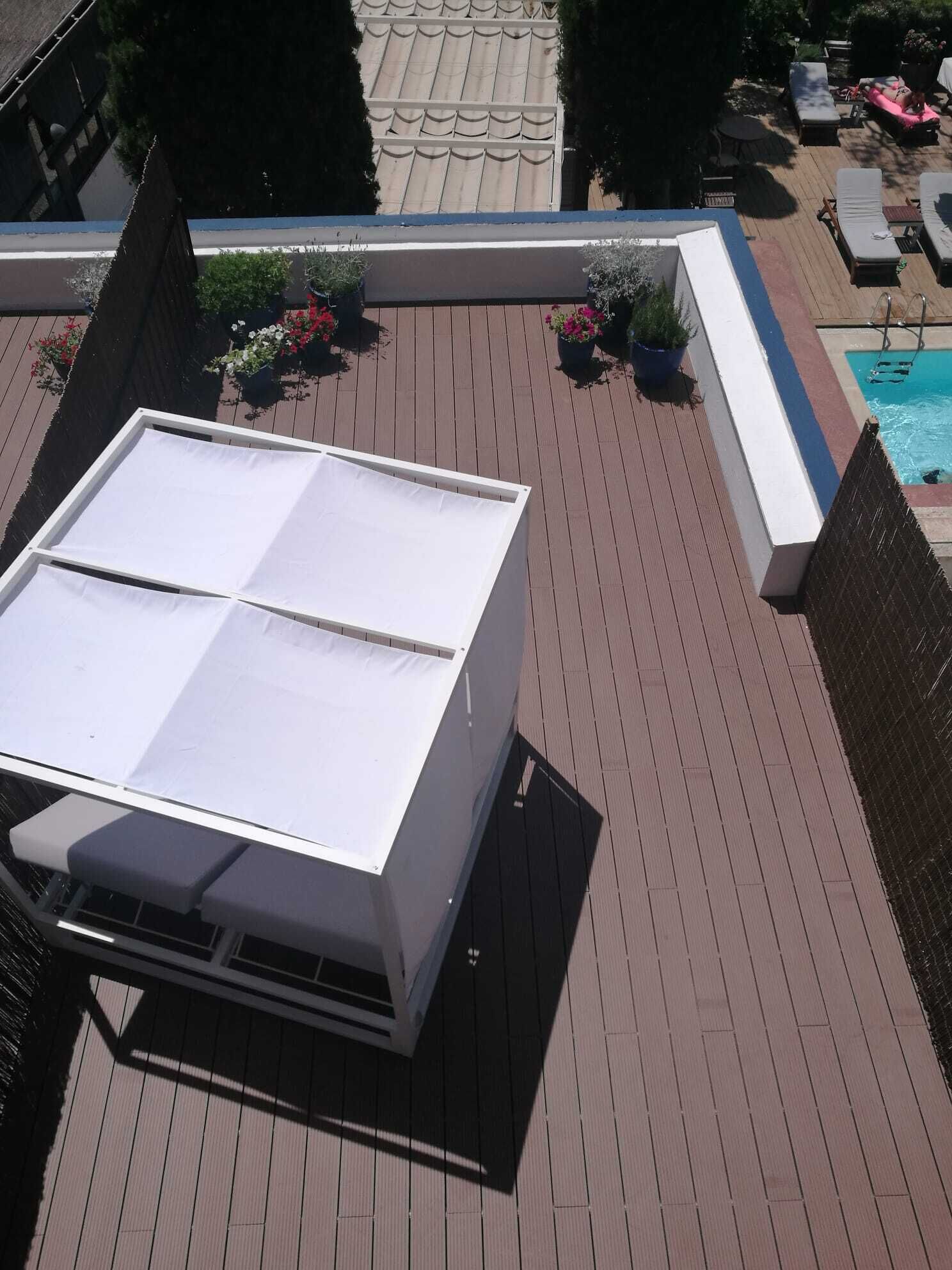 Une terrasse sur le toit avec une piscine, des chaises longues et des plantes en pot.