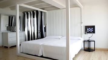 A bedroom with a bed, a dresser, a mirror, a curtain, and a small table with a lamp.