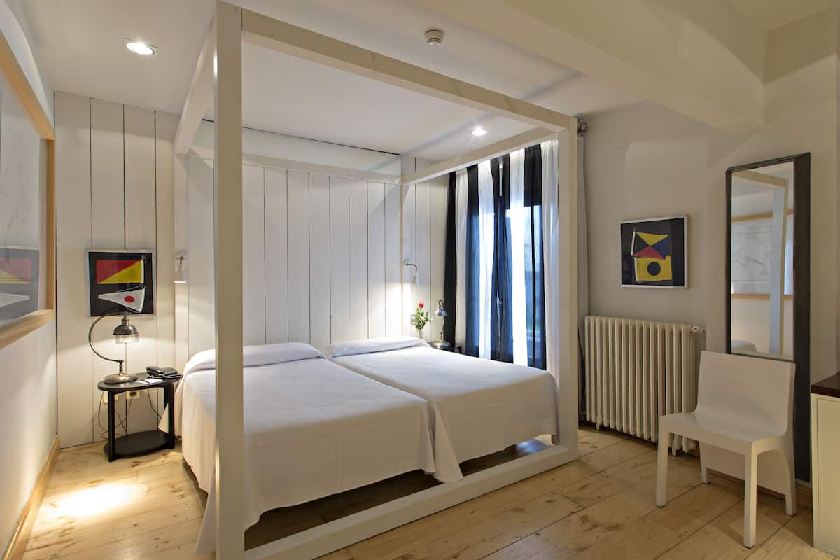 A modern bedroom with a large bed, bedside tables, a chair, and artwork on the walls.