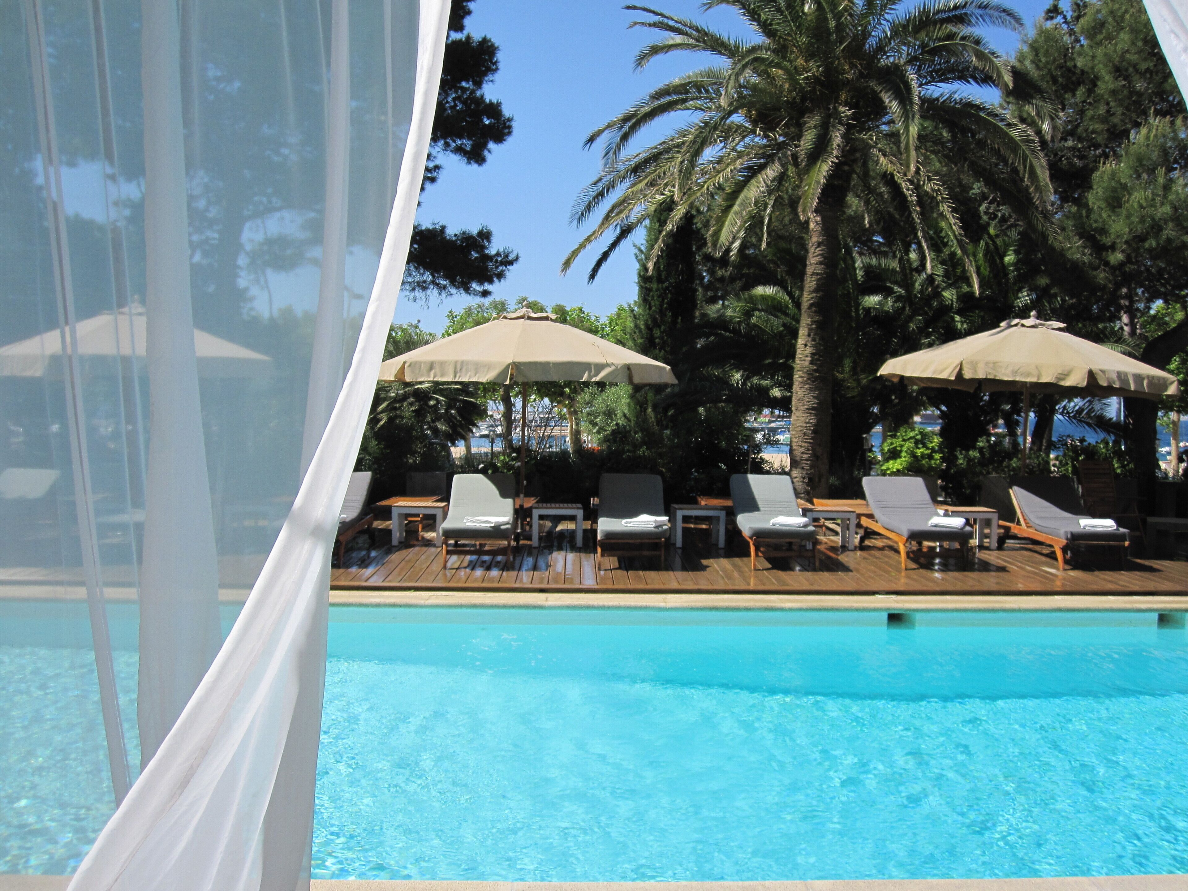 Een buitenzwembad, parasols bij het zwembad en ligstoelen