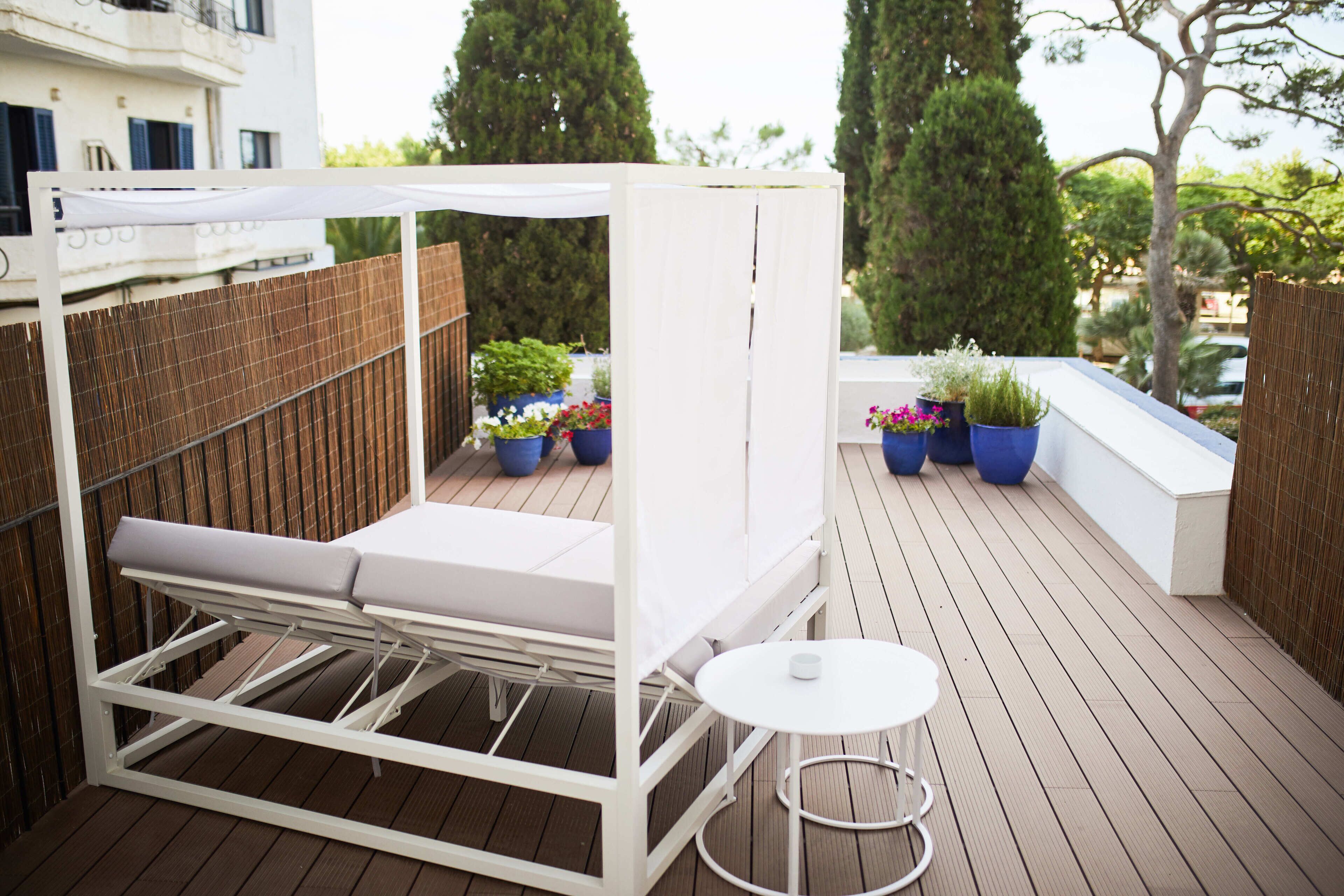 A balcony with a white canopy, a white metal table, and potted plants.