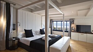 Habitación de hotel con dos camas, televisión y vista al mar.