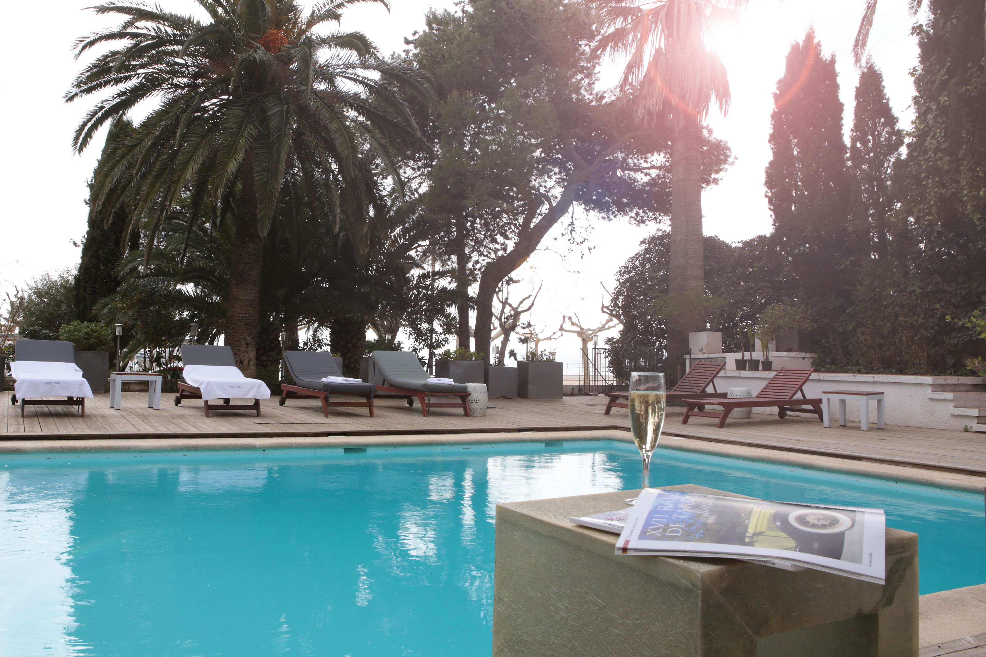 Un espace piscine avec des chaises longues et une coupe de champagne.