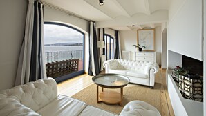 Un salón amplio con un sofá blanco, una mesita redonda y vistas al mar a través de ventanas grandes.