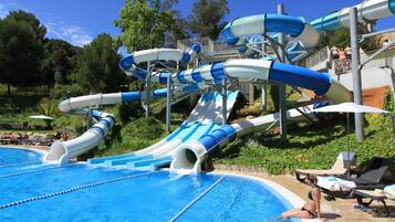 Una piscina al aire libre, sombrillas, sillones reclinables de piscina