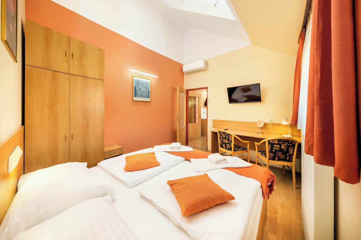 A hotel room with two beds, a desk, a TV, and a wardrobe.