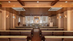 A church interior with wooden pews, a central altar, and religious icons. - Crisol Tres Pastorinhos (Ourem)