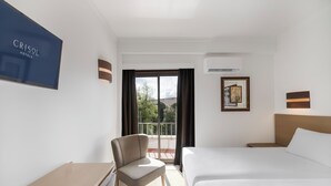A hotel room with a bed, a chair, a desk, a window with curtains, and a wall-mounted sign. - Crisol Tres Pastorinhos (Ourem)