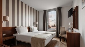 A hotel room with two beds, a desk, a chair, a TV, and a window with curtains. - Crisol Tres Pastorinhos (Ourem)