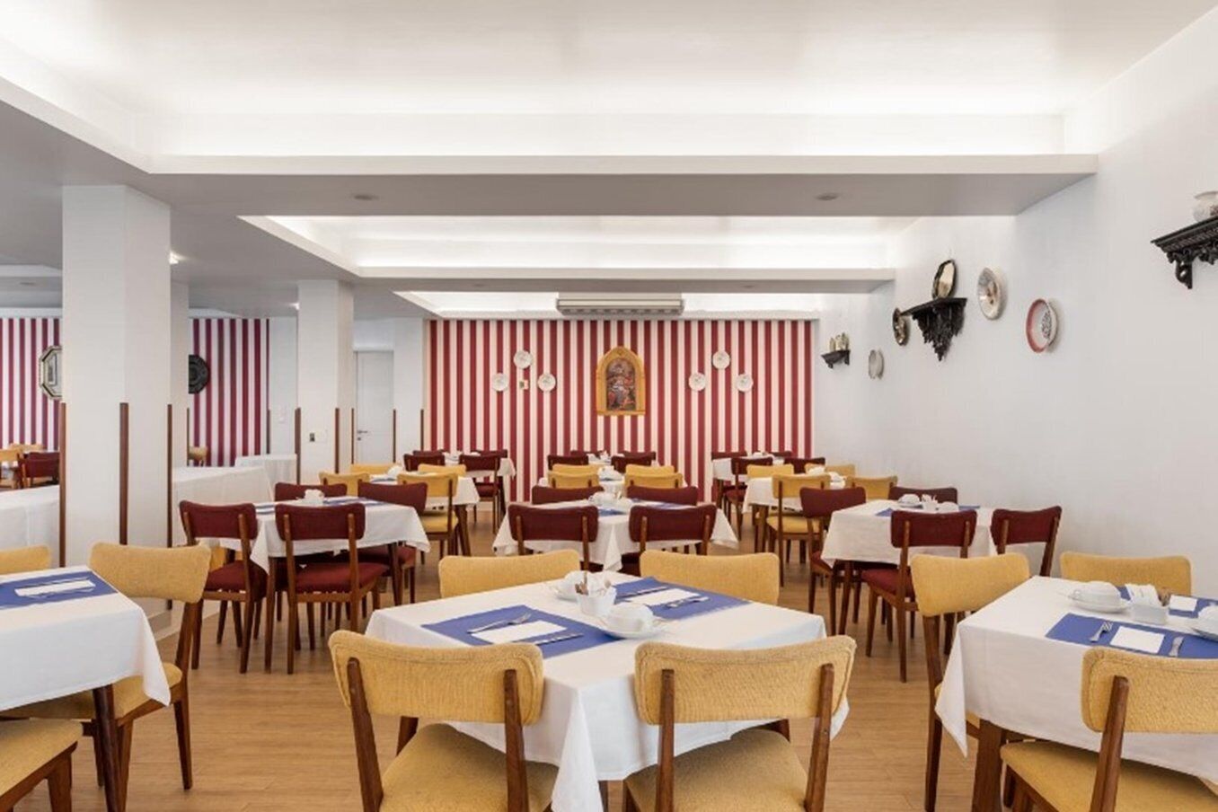 A dining area with tables and chairs, striped walls, and a ceiling light fixture.