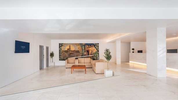A spacious lobby with a modern reception desk, a beige sofa, and a large mural on the wall. - Crisol Tres Pastorinhos (Ourem)