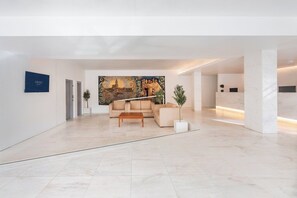 A modern lobby with a sofa, a coffee table, a reception desk, and a large mural on the wall. - Crisol Tres Pastorinhos (Ourem)