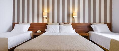 Quarto de hotel com uma cama grande, duas mesas de cabeceira e uma parede listrada.