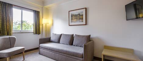 A modern living room with a grey sofa, a wooden bench, and a framed picture on the wall.