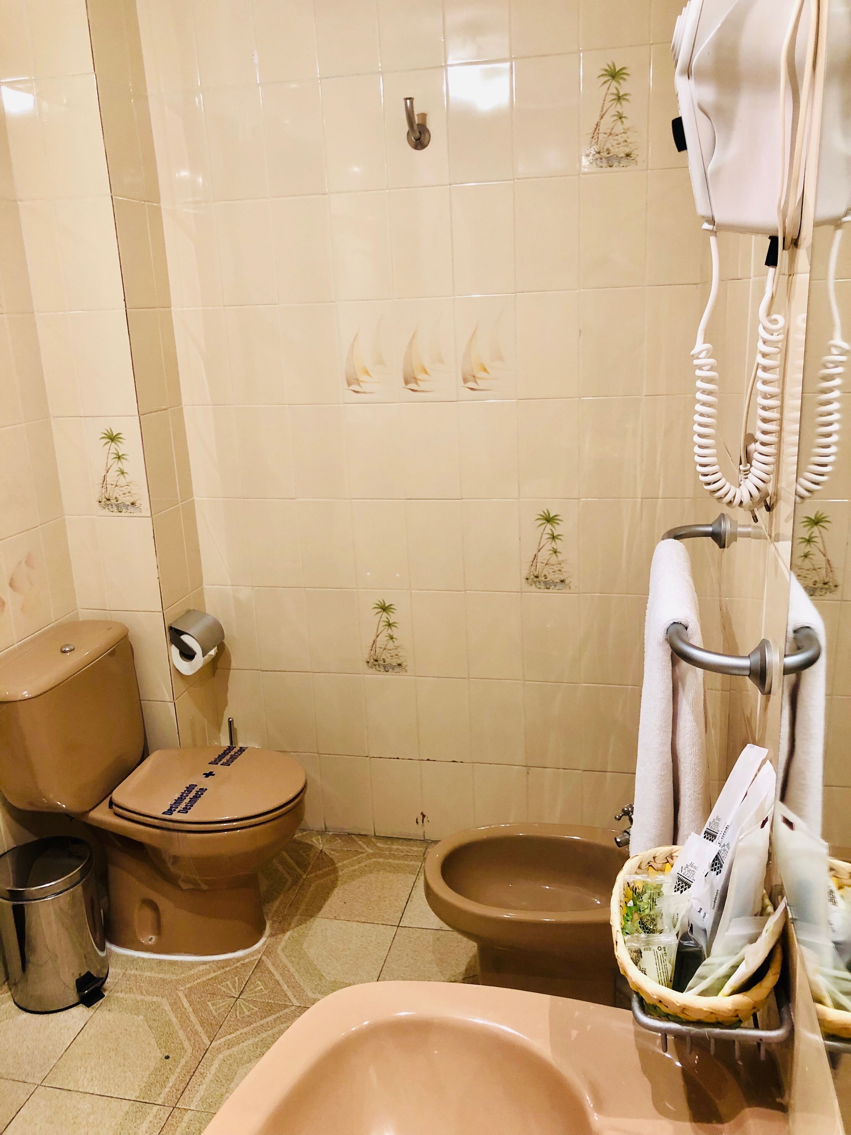 A bathroom with a toilet, bidet, and a sink with a towel rack.
