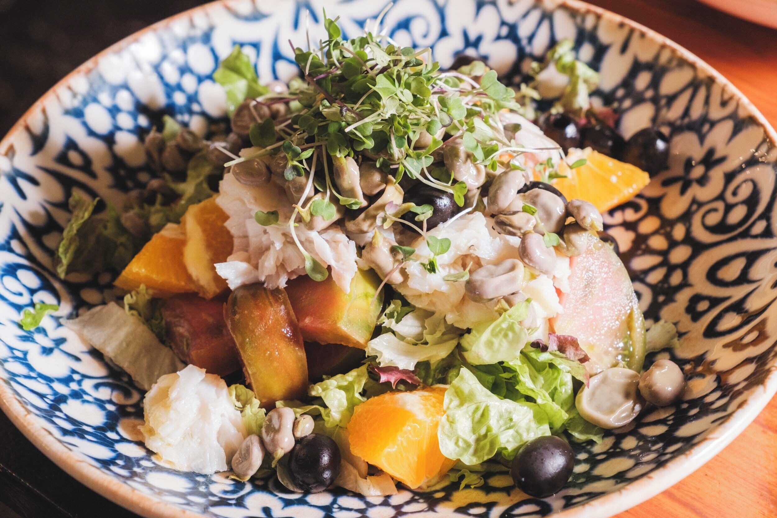 A bowl of salad with various vegetables and sprouts.