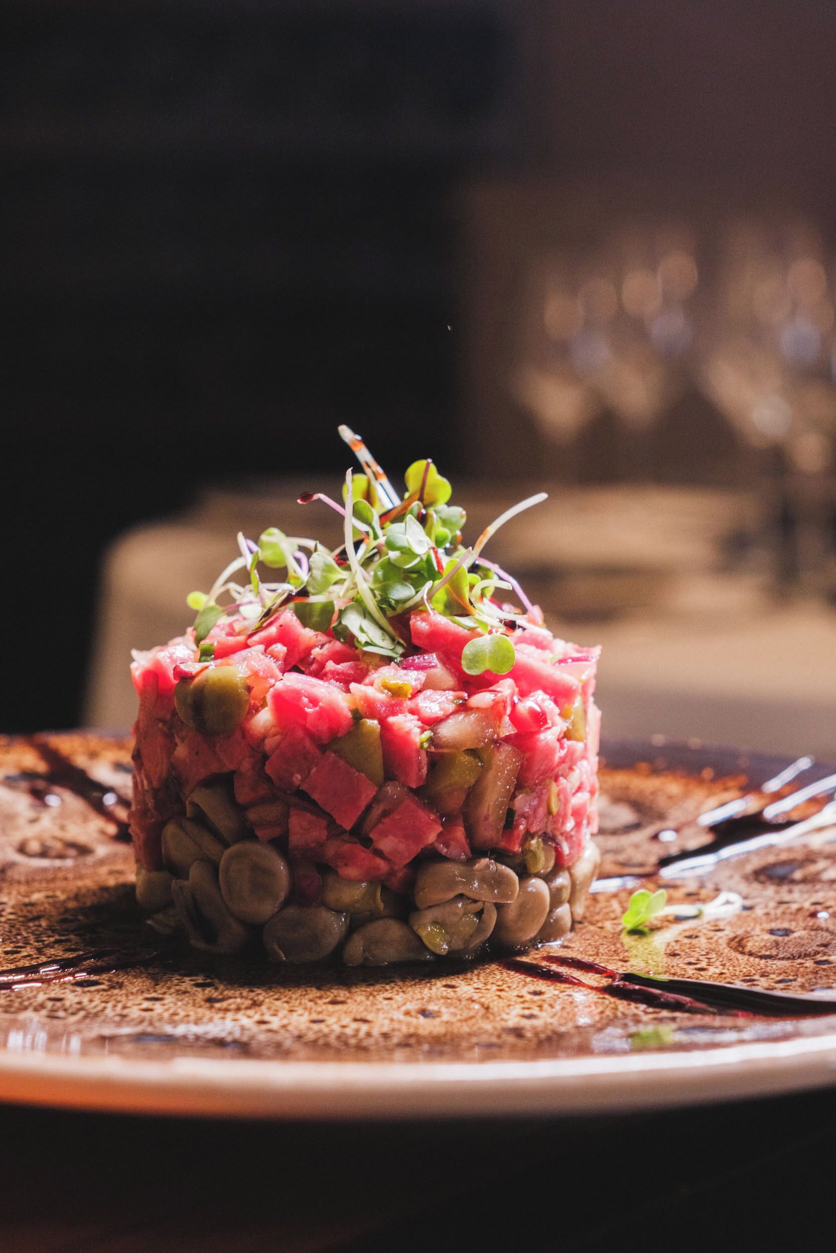 A dish of steak tartare with beans and sprouts on a plate.