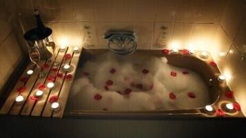A bathtub with rose petals and candles.