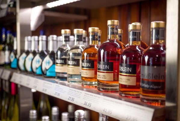 A shelf with various bottles of alcohol, including brands like 'MOBILEIN' and 'MALTIS 5 YRS'.
