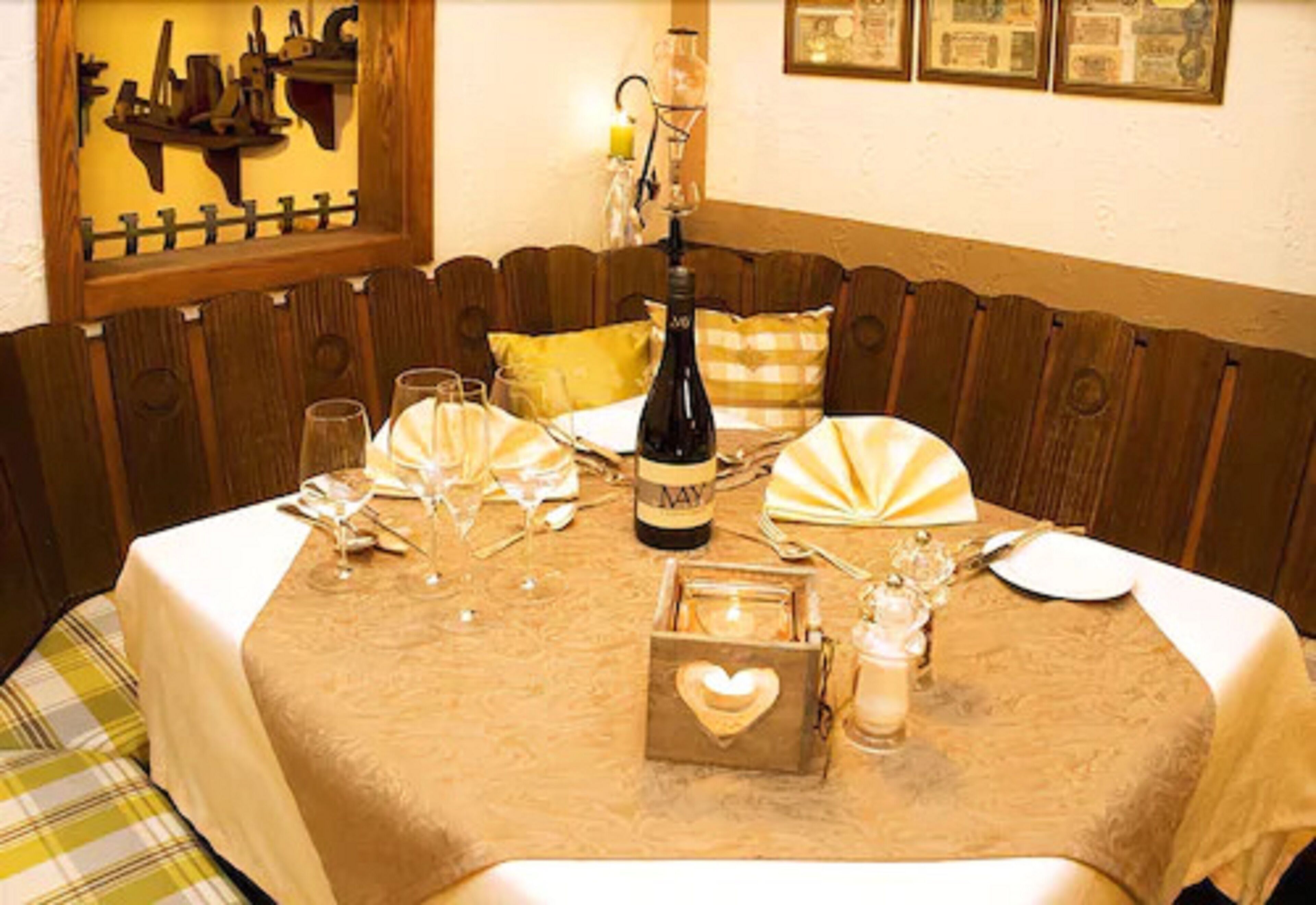 A dining table set with wine glasses, a bottle of wine, and a heart-shaped box.