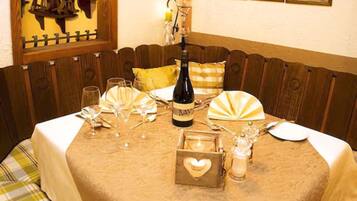A dining table set with wine glasses, a bottle of wine, and a heart-shaped box.