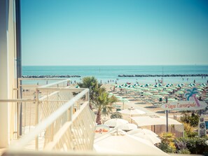 Uitzicht op het strand vanaf een balkon, met ligbedden en parasols.