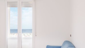 Un dormitorio con cama, vista a la playa y un juego de toallas blancas.