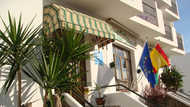 Entrada de hotel com uma escadaria, uma placa indicando "Hotel Leros Jotas" e bandeiras, incluindo a bandeira da União Europeia.