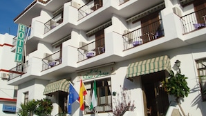 Um hotel com vários andares, varandas, um aviso indicando uma garagem e bandeiras.