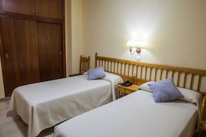 A hotel room with two single beds, a wooden headboard, a bedside table with a lamp, and a telephone. - Hotel Tres Jotas (Conil de la Frontera)