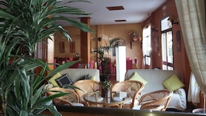 Um quarto aconchegante com mobiliário de vime, uma planta grande em vaso e um sofá com almofadas.