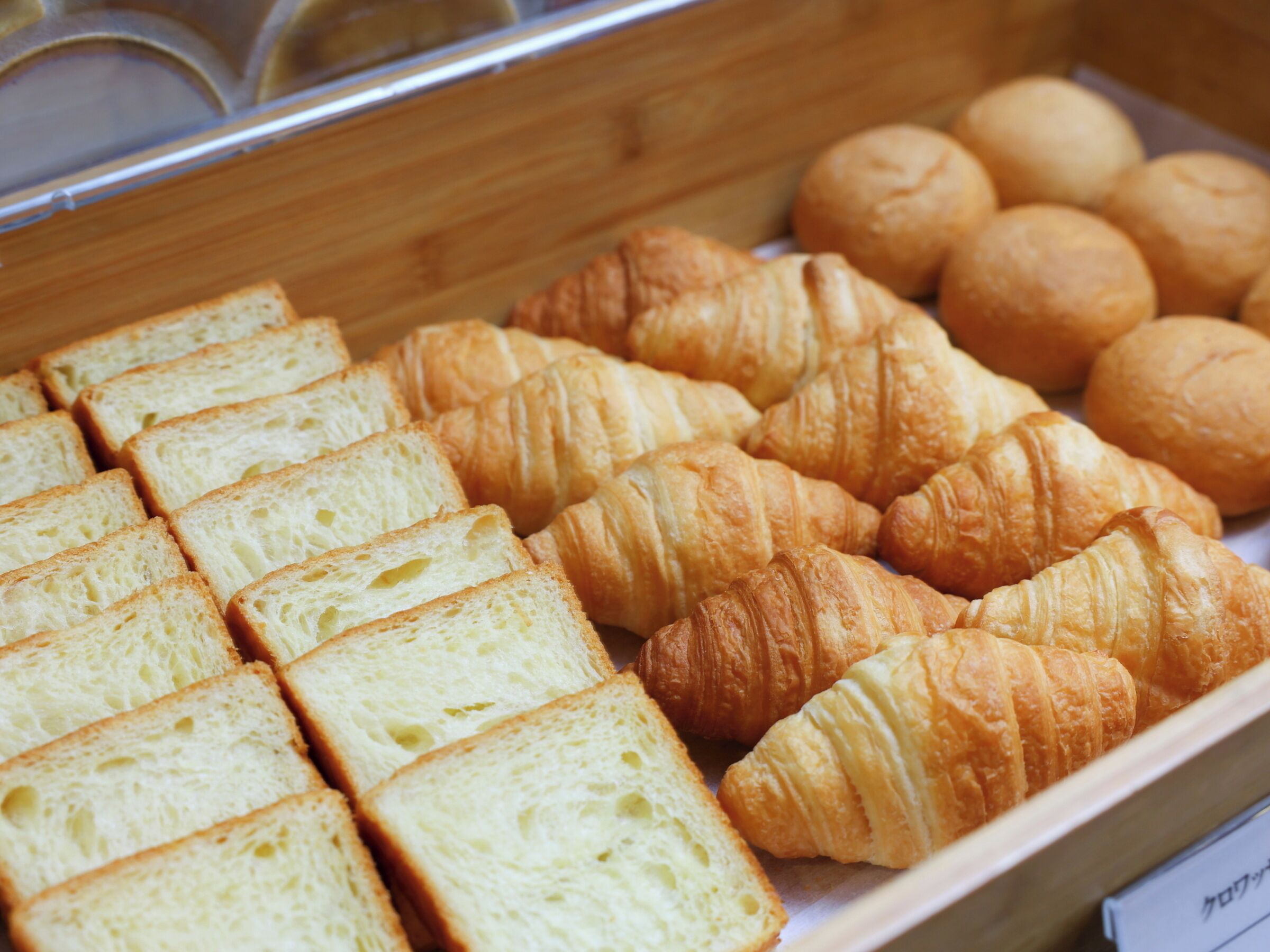 Una vitrina de panadería con panes y pasteles diversos.