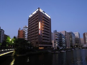 Un grand hôtel à plusieurs étages, avec une enseigne bien visible au sommet et une vue sur le front de mer.