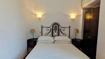Una cama bien hecha con sábanas blancas, dos lámparas de noche y un cabecero decorativo.