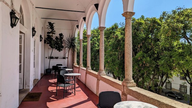 A covered outdoor area with tables and chairs, columns, and potted plants. - Hotel Solar De Monfalim (Évora)