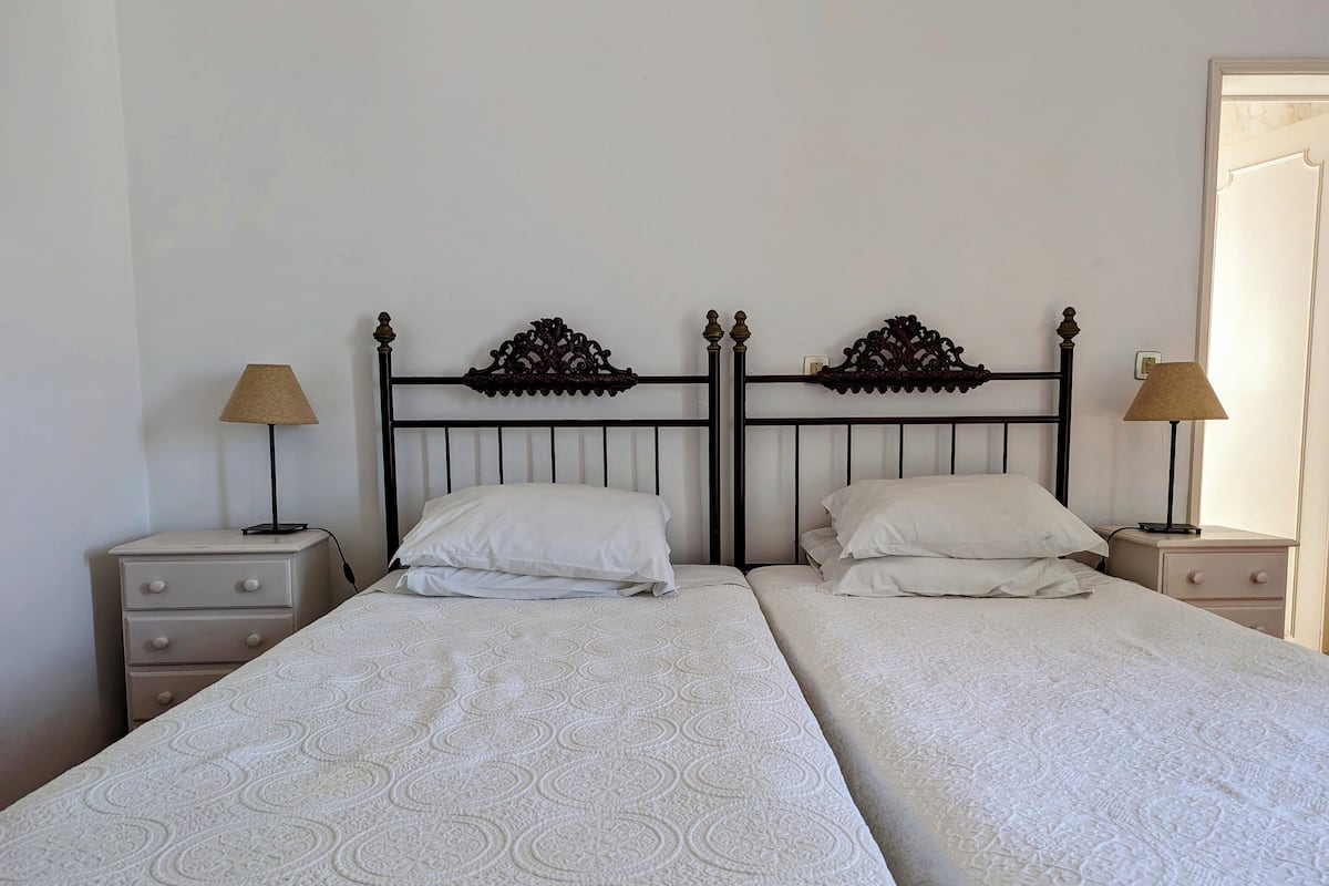 A double bed with a patterned bedspread, two bedside tables with lamps, and a decorative headboard.