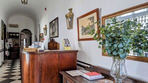 A reception area with a wooden desk, framed pictures, and a potted plant. - Hotel Solar De Monfalim (Évora)