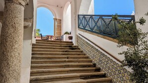 A stone staircase leading to a terrace with outdoor seating, surrounded by white walls and columns. - Hotel Solar De Monfalim (Évora)