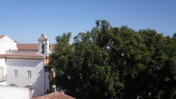 Un edificio con tetto in tegole, un campanile e un albero di grandi dimensioni di fronte.