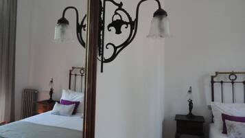 Een hotelkamer met een groot bed, een nachtkastje met een lamp en een wandlamp.
