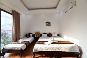 Hotelkamer met twee bedden, een groot raam met gordijnen, een wandairconditioner en een lijst met een foto.