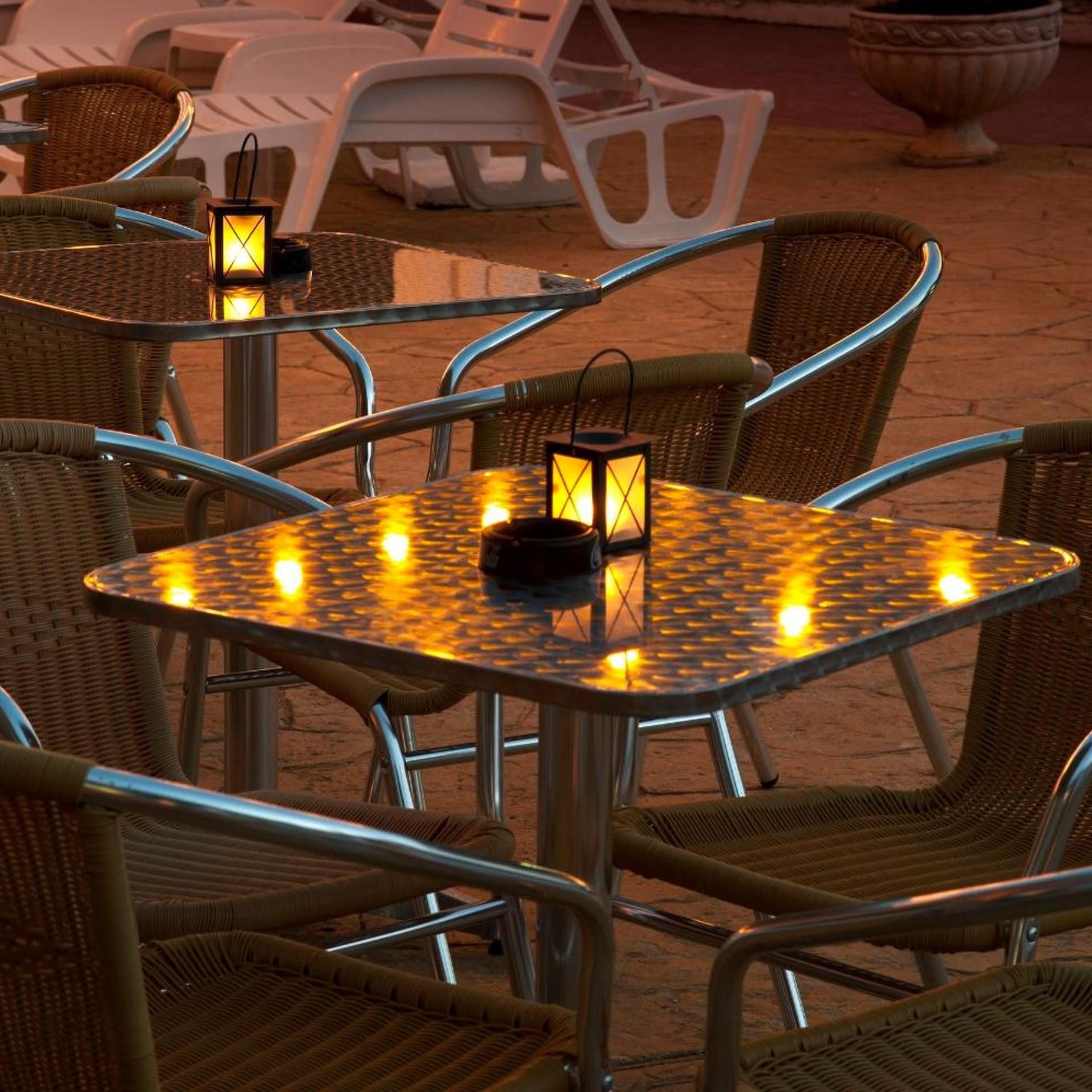 Outdoor wicker chairs and tables with metal frames, arranged in a patio setting.