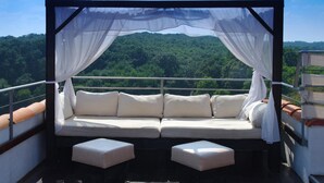 A balcony with a white cushioned sofa and ottomans, draped with sheer white curtains, overlooking a forested landscape. - Resort Bella Vista Beach Club (Sinemoretz)