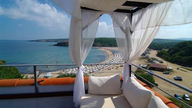 A balcony with a view of a beach, a sofa, and a railing. - Resort Bella Vista Beach Club (Sinemoretz)