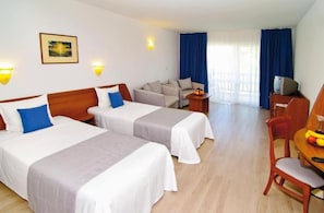 A hotel room with two beds, a sofa, a dining table with chairs, a TV, and a window with curtains. - Bella Vista Beach Club (Tsarevo)