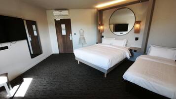 Habitación de hotel con dos camas, un televisor de pantalla plana, un espejo y una puerta.