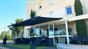 Exterior de un hotel con un área de estar al aire libre cubierta, un letrero que dice