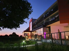 Un edificio moderno con fachada de vidrio, un letrero visible que dice "ALL IN ONE" y un área de entrada bien iluminada.